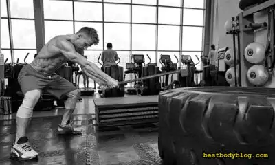 Спортсмен виконує удар молотом по покришці під час функціонального тренування в залі