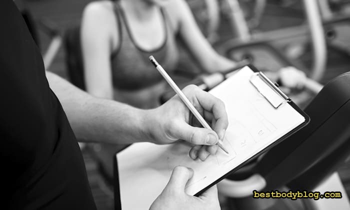 Фітнес тренер записує індивідуальну програму тренувань для дівчини на планшеті