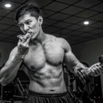 Добова норма білка для спортсмена. Атлет із гантеллю їсть правильну їжу під час тренування у залі.